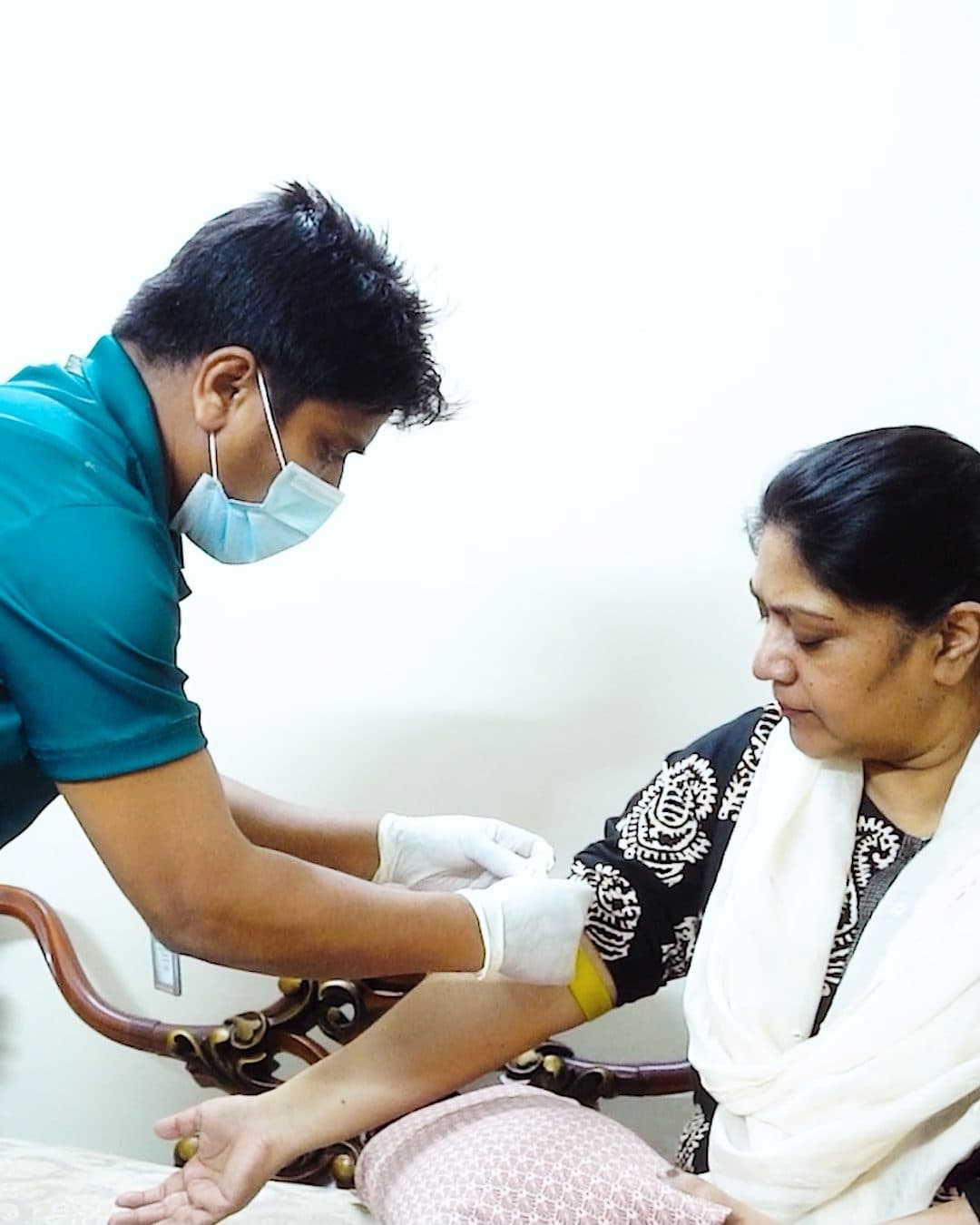 An Ascent Health phlebotomist collecting a sample at a patient's home